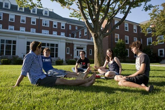 Studenci Tufts University w przerwie między zajęciami, siedzący na trawniku na kampusie.